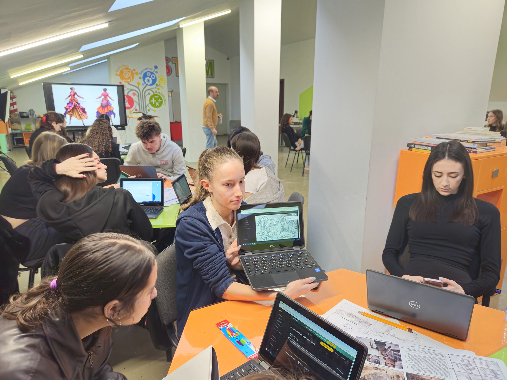 Student holding laptop showing architectural or scene design, collaboration at Sava Dobroplodni